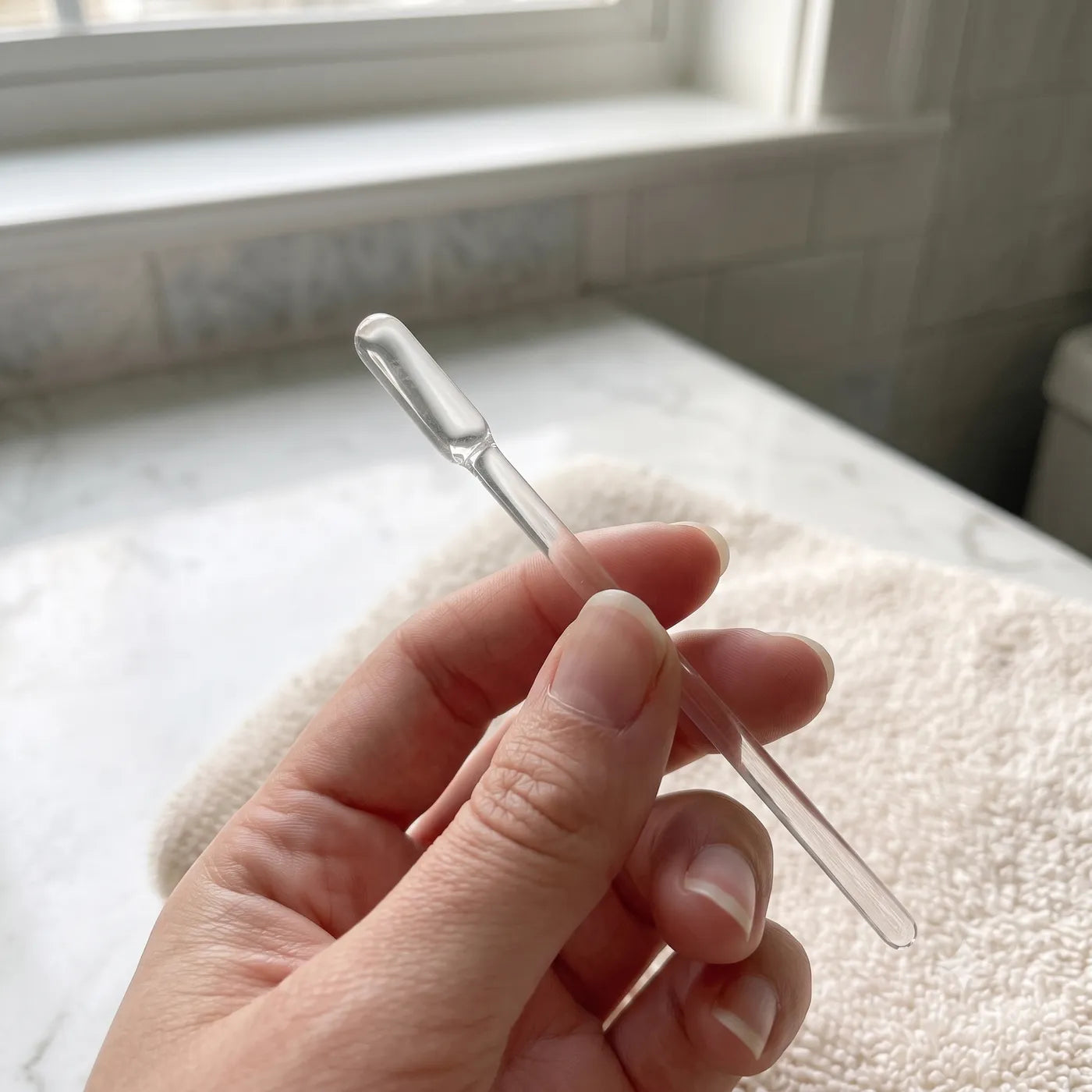 The Earclear stick held between two fingers, showing its small size